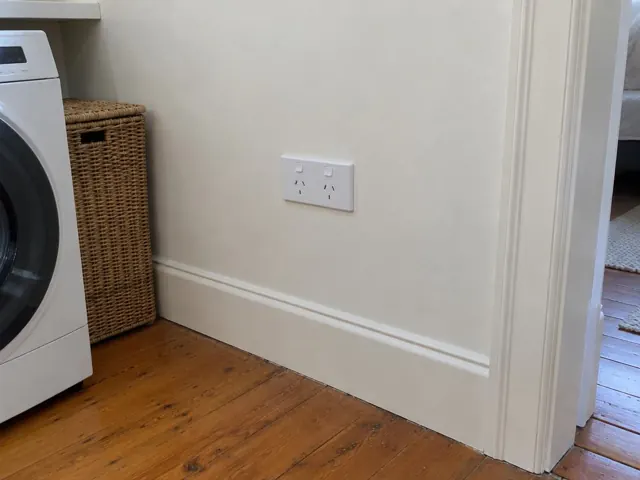 Double power point on a painted wall in a laundry room with timber floor and washing machine in Bellevue Hill