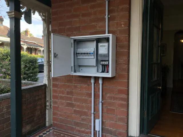 Outdoor switchboard mounted on a brick exterior wall beside a front doorway in Edgecliff